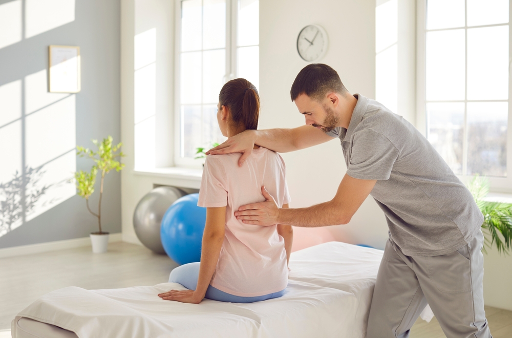 Chiropractor helping patient with scoliosis and back pain