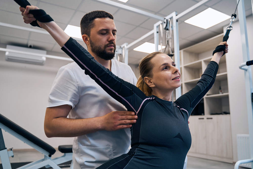 Physiotherapist treats hands of woman patient with stretching elastic band