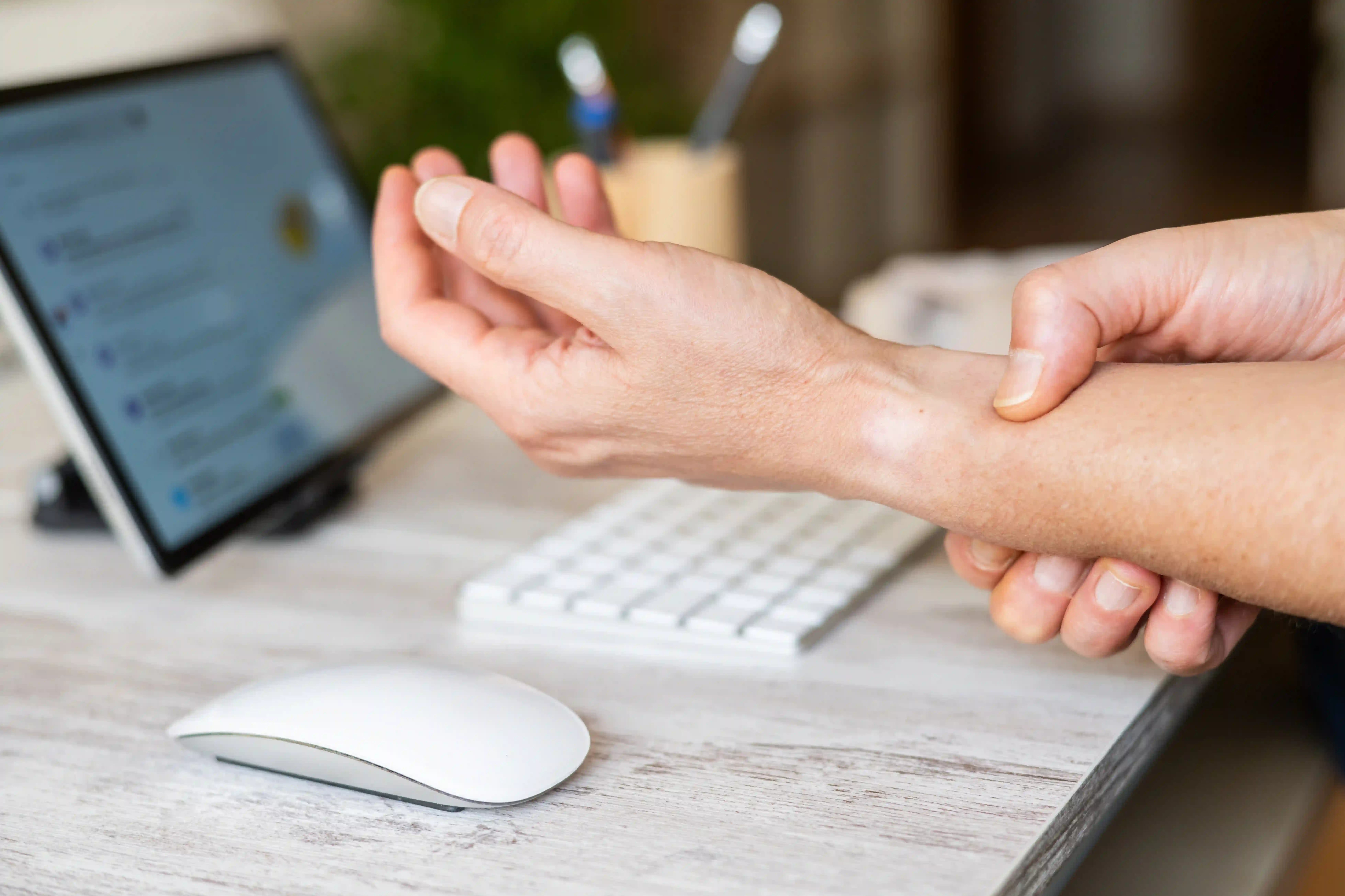 Person with carpal tunnel syndrome experiencing wrist pain while working on a computer
