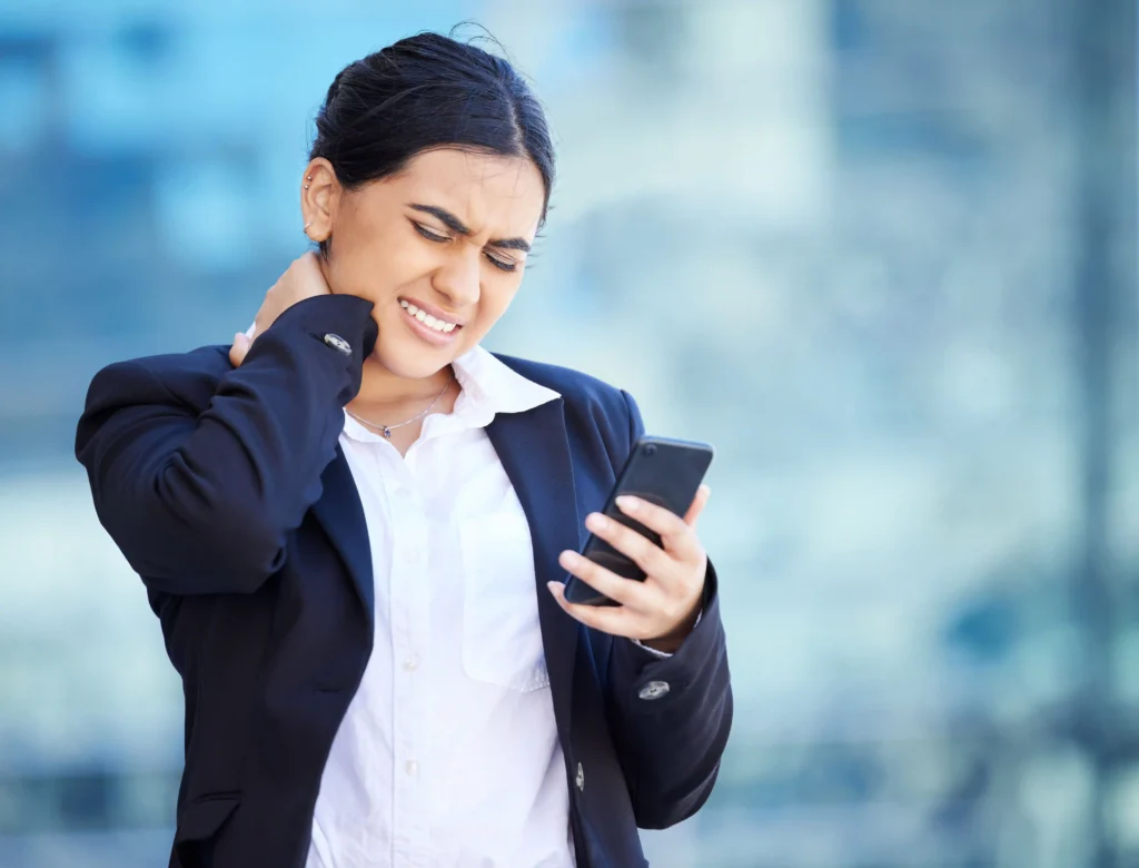 Woman experiencing neck pain from frequent phone use