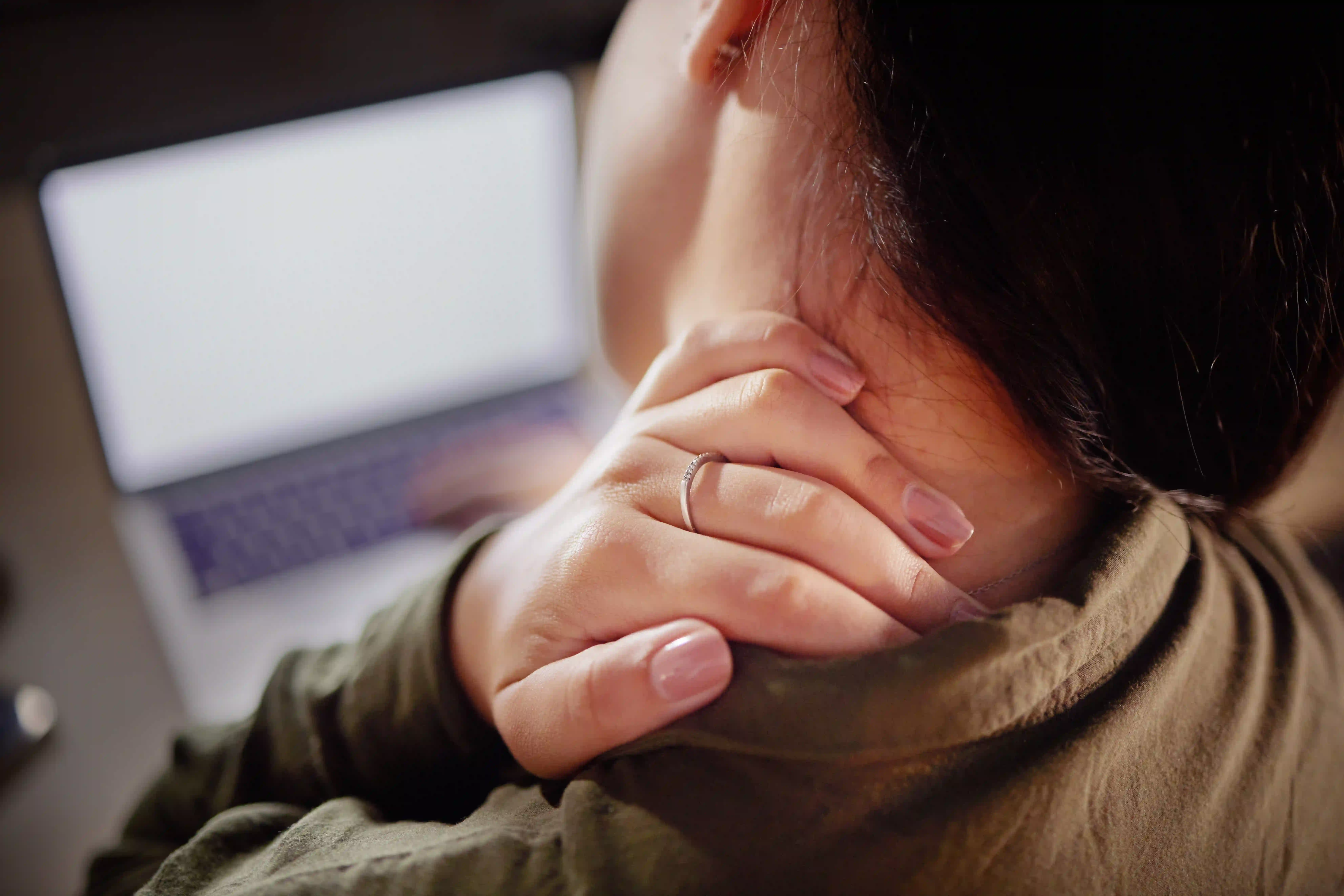 Woman experiencing a stiff neck while sitting at a desk